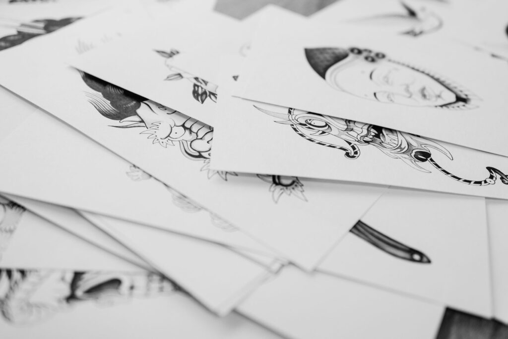 Collection of hand-drawn tattoo flash designs spread on a workspace